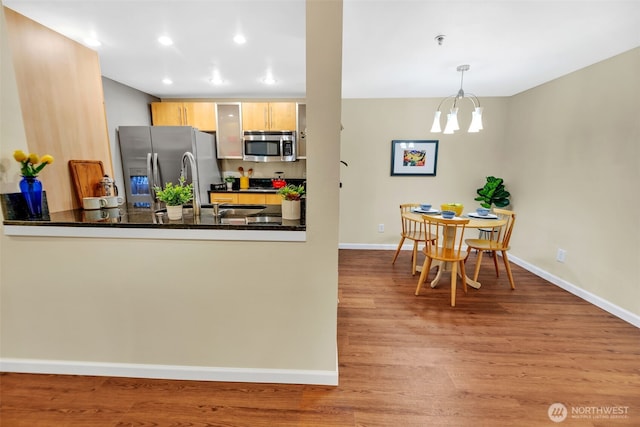 975 Aberdeen Ave NE Unit F207, Renton, WA 98056 - kitchen with baseboards, dark countertops, appliances with stainless steel finishes, a peninsula, and wood finished floors