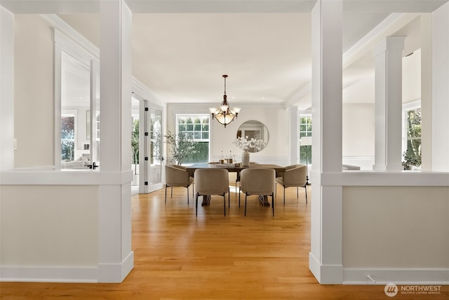 dining space featuring a notable chandelier, baseboards, ornamental molding, and light wood-style floors
