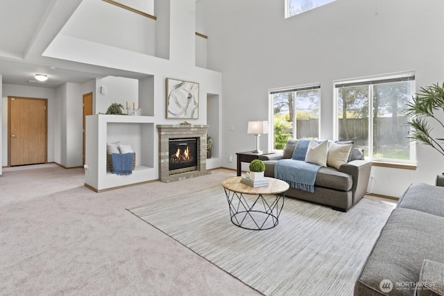 carpeted living room featuring a fireplace, baseboards, a towering ceiling, and built in features
