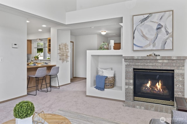 carpeted living room with a fireplace, baseboards, and recessed lighting