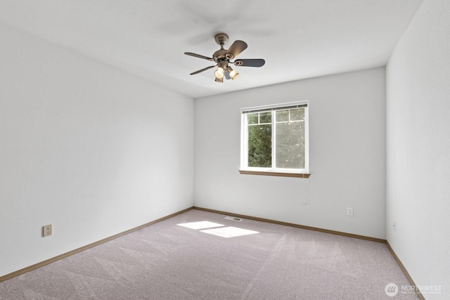 carpeted spare room with ceiling fan and baseboards