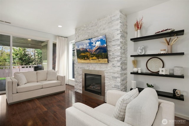 living room featuring recessed lighting, a fireplace, visible vents, and wood finished floors