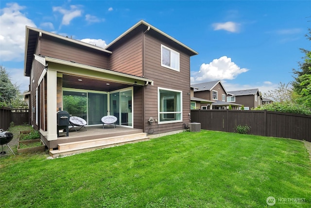 back of house with a deck, a lawn, and a fenced backyard