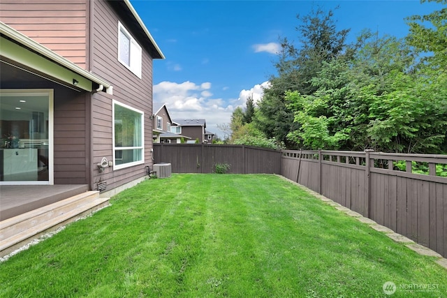 view of yard with a fenced backyard and central AC