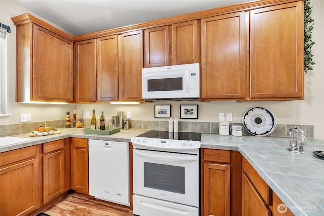 kitchen with white appliances, brown cabinetry, and light wood finished floors