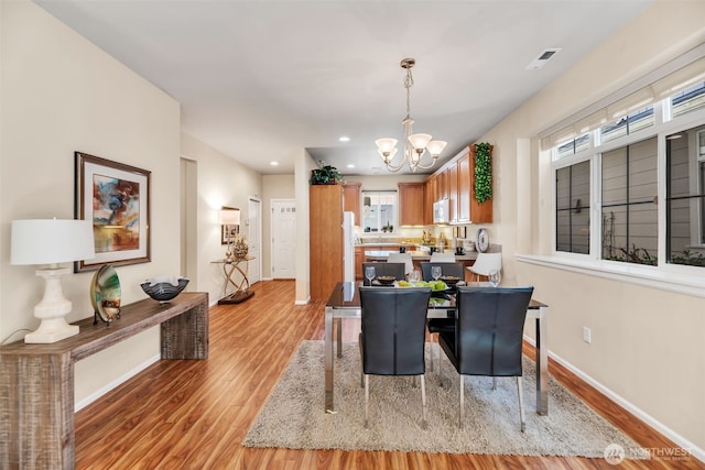 dining space featuring a notable chandelier, light wood-style floors, recessed lighting, baseboards, and visible vents