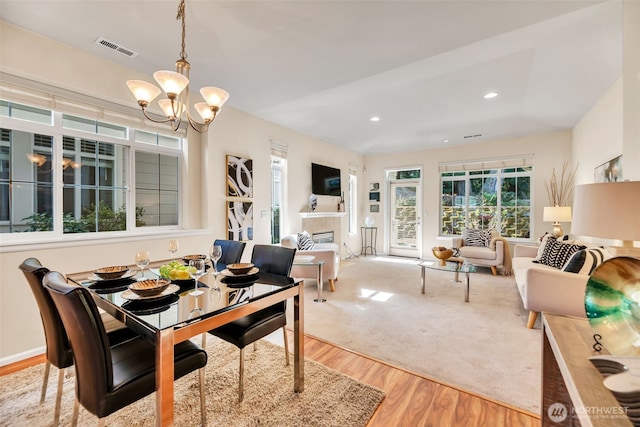 dining room featuring visible vents, a tiled fireplace, wood finished floors, a notable chandelier, and recessed lighting