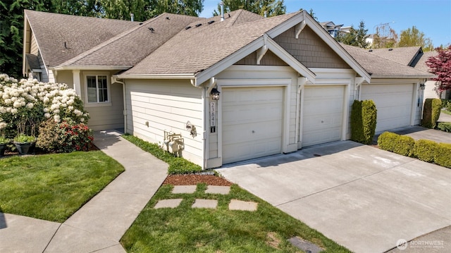 view of front of property with driveway, a shingled roof, a front yard, and a garage