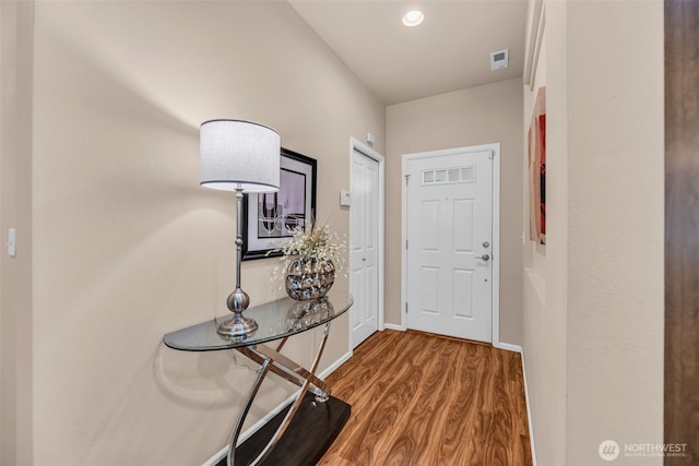 doorway to outside featuring baseboards, visible vents, and wood finished floors