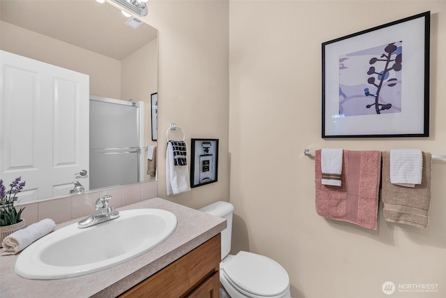 bathroom with vanity, a shower with shower door, and toilet
