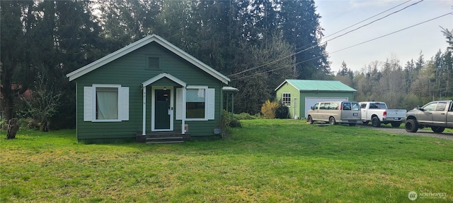 view of front of house with entry steps, a front lawn, an outdoor structure, and a forest view