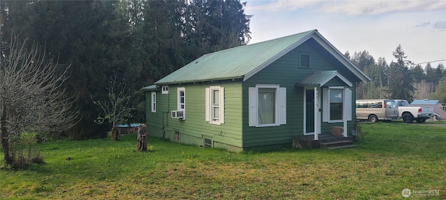 bungalow-style home with a front lawn, cooling unit, and metal roof