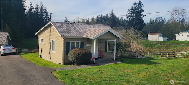 view of front of home featuring a front lawn, fence, metal roof, and driveway