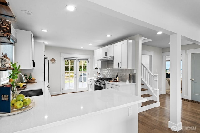 3236 15th Ave S, Seattle, WA 98144 - kitchen with gas stove, under cabinet range hood, a sink, dark wood-style flooring, and white cabinetry