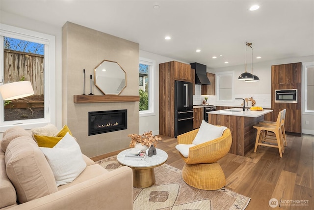 living room featuring recessed lighting, a tiled fireplace, and light wood-type flooring