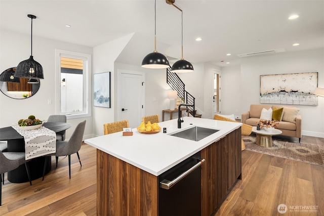 kitchen with recessed lighting, wood finished floors, dishwasher, light countertops, and a sink
