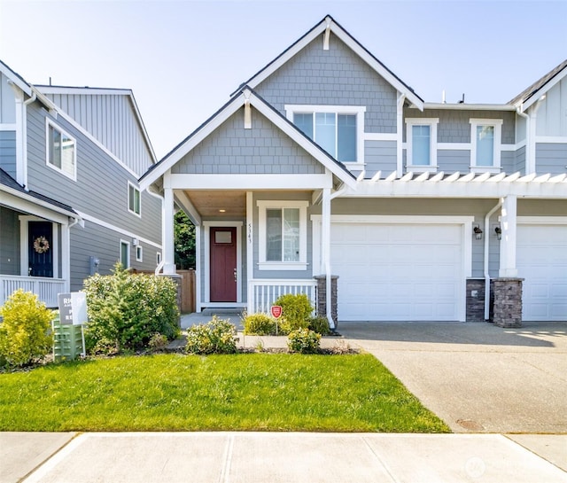 craftsman inspired home with a front lawn, driveway, an attached garage, and covered porch
