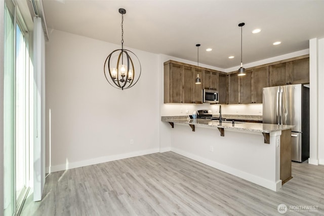 kitchen featuring a kitchen breakfast bar, stainless steel appliances, recessed lighting, light wood finished floors, and a peninsula