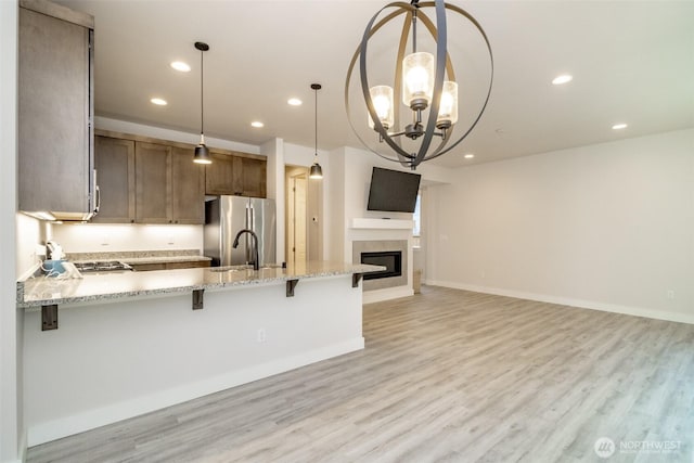 kitchen featuring recessed lighting, a peninsula, freestanding refrigerator, light wood finished floors, and open floor plan