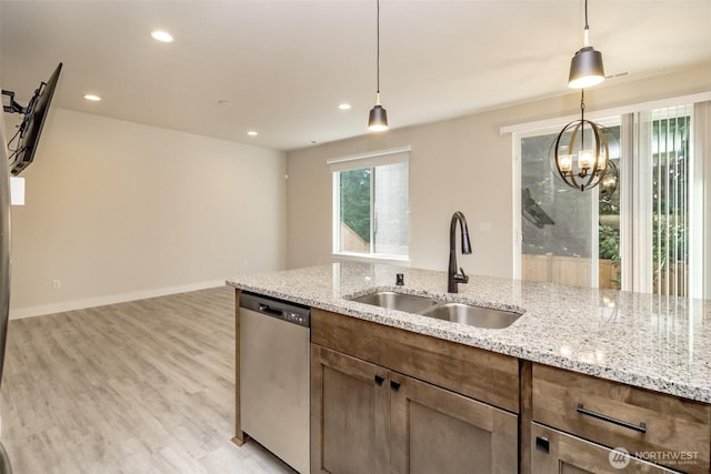 kitchen featuring a sink, light wood-style floors, a notable chandelier, pendant lighting, and dishwasher
