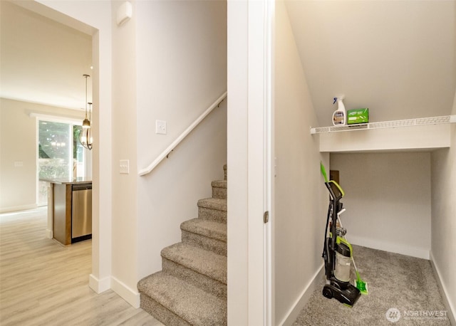 stairs with baseboards, wood finished floors, and an inviting chandelier