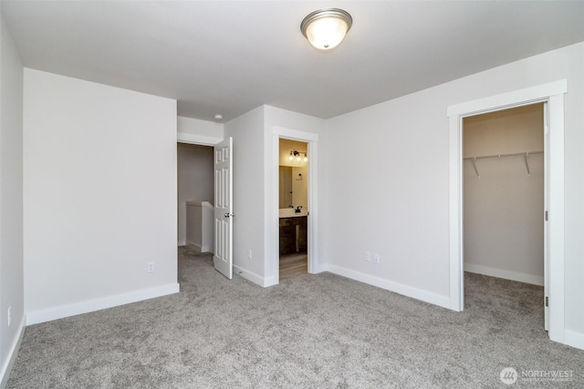 unfurnished bedroom featuring connected bathroom, a closet, baseboards, carpet floors, and a walk in closet