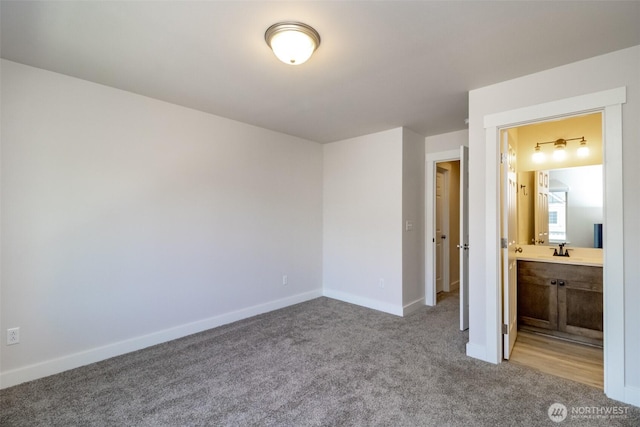 unfurnished bedroom featuring connected bathroom, a sink, carpet floors, and baseboards