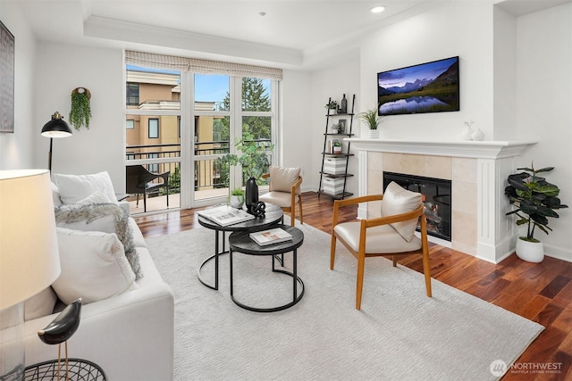 10047 Main St Unit 413, Bellevue, WA 98004 - living area featuring a tiled fireplace, wood finished floors, recessed lighting, baseboards, and a tray ceiling