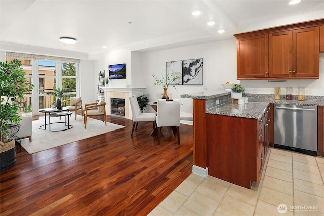 10047 Main St Unit 413, Bellevue, WA 98004 - kitchen with stainless steel dishwasher, light wood-style floors, stone counters, a tiled fireplace, and recessed lighting