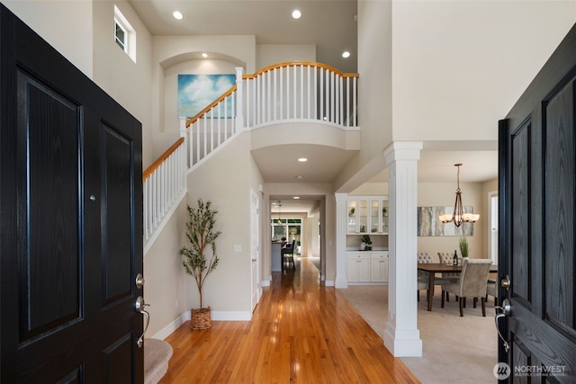 foyer featuring recessed lighting, stairs, light wood finished floors, and a high ceiling