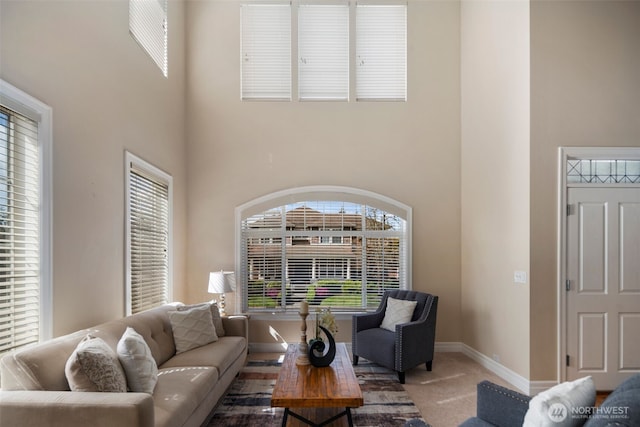 living room with a towering ceiling, baseboards, and carpet floors