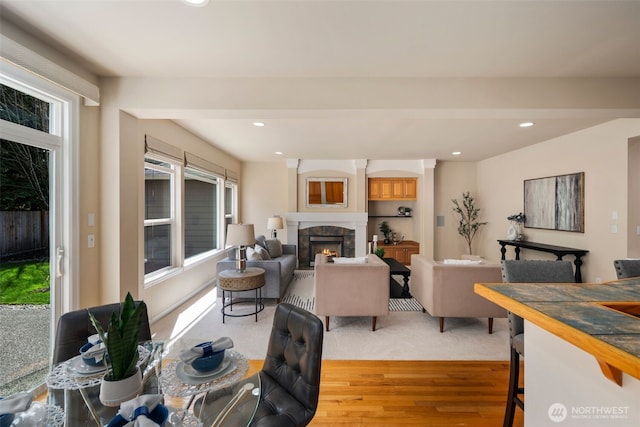 living room featuring recessed lighting, light wood-style flooring, and a warm lit fireplace