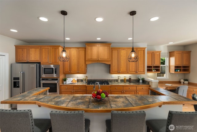kitchen featuring open shelves, dark countertops, stainless steel appliances, brown cabinets, and a breakfast bar area