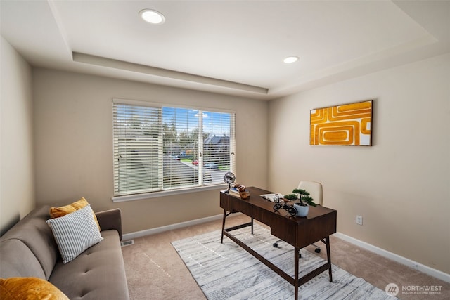 office featuring light carpet, baseboards, and a raised ceiling