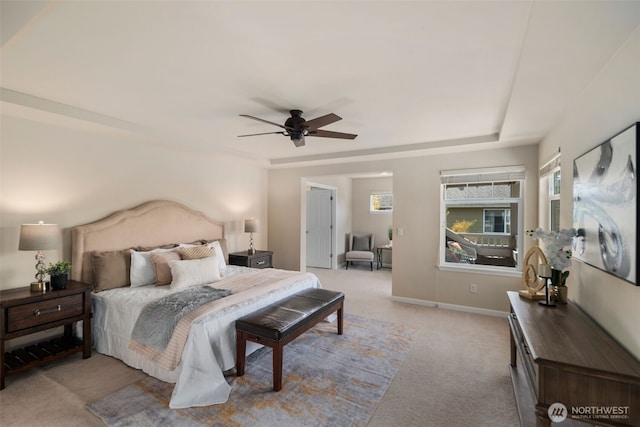 bedroom featuring carpet floors, baseboards, multiple windows, and a raised ceiling