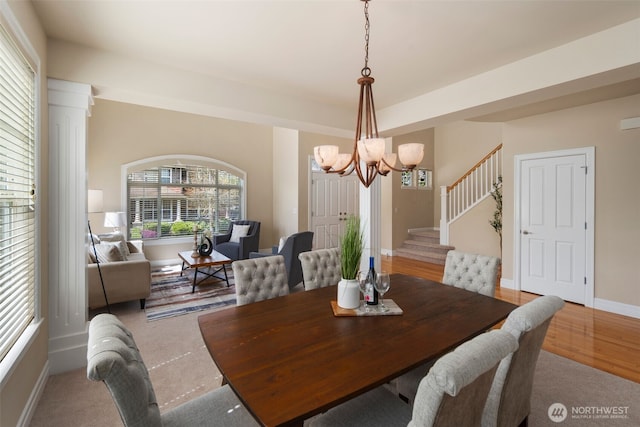 dining space featuring a notable chandelier, baseboards, and stairway
