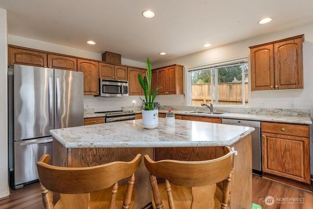 kitchen featuring a kitchen island, recessed lighting, a sink, dark wood finished floors, and stainless steel appliances
