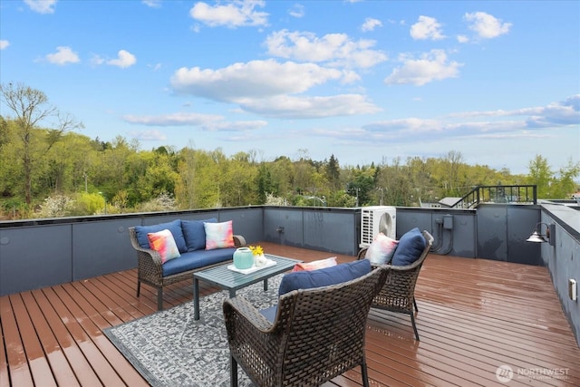 wooden terrace with a wooded view and an outdoor living space
