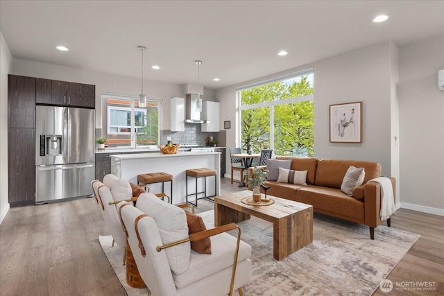 living room with light wood-type flooring, baseboards, and recessed lighting
