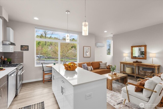 kitchen featuring open floor plan, appliances with stainless steel finishes, a wall unit AC, and modern cabinets