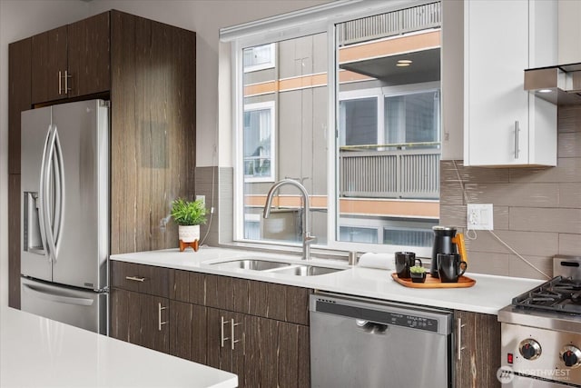 kitchen featuring dark brown cabinetry, tasteful backsplash, light countertops, a sink, and stainless steel appliances