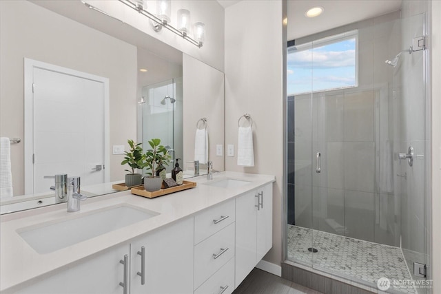 bathroom featuring a sink, a shower stall, and double vanity
