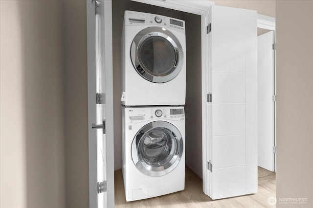 laundry room featuring stacked washer / drying machine, laundry area, and wood finished floors
