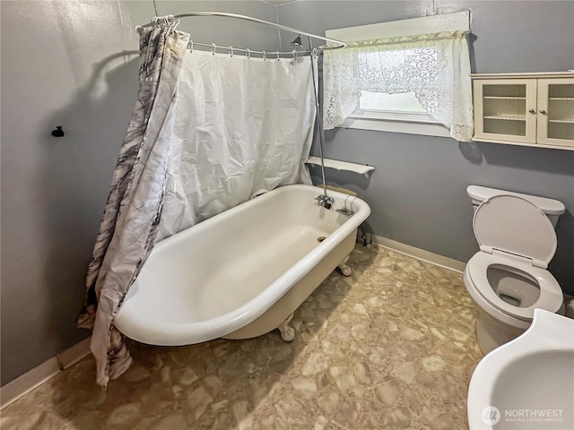 bathroom featuring a sink, shower / tub combo, toilet, and baseboards