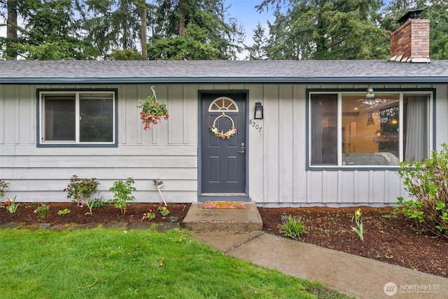8207 Woodbourne Dr SW, Lakewood, WA 98499 - doorway to property with board and batten siding, a shingled roof, and a chimney