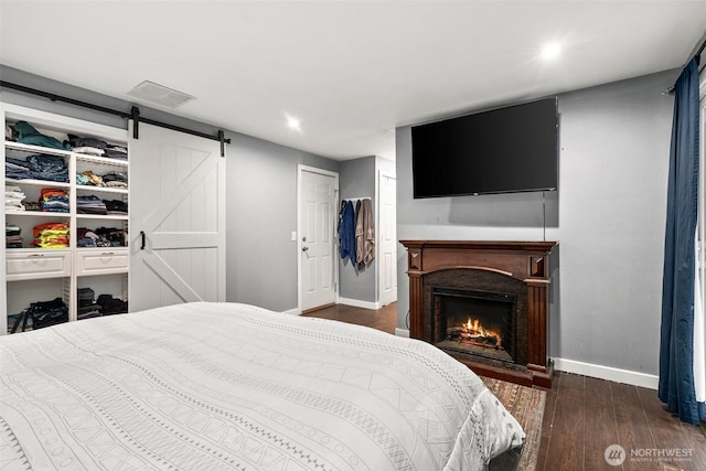 8207 Woodbourne Dr SW, Lakewood, WA 98499 - bedroom with visible vents, baseboards, a barn door, wood finished floors, and a lit fireplace