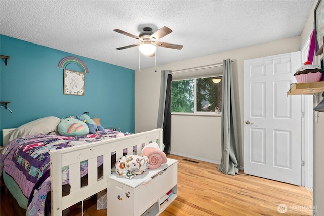 8207 Woodbourne Dr SW, Lakewood, WA 98499 - bedroom with visible vents, a textured ceiling, a ceiling fan, and light wood-style flooring