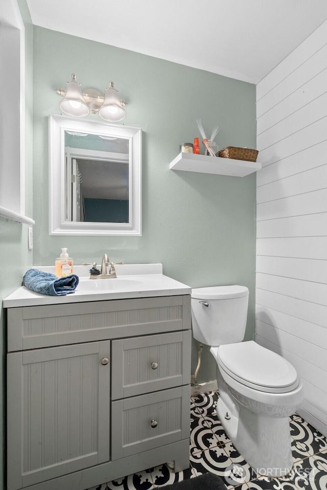 8207 Woodbourne Dr SW, Lakewood, WA 98499 - bathroom with wood walls, tile patterned floors, vanity, and toilet