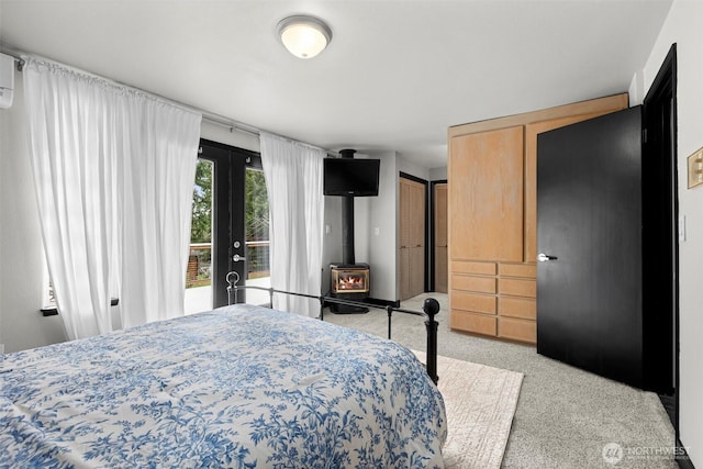 carpeted bedroom featuring french doors, a wood stove, and access to outside