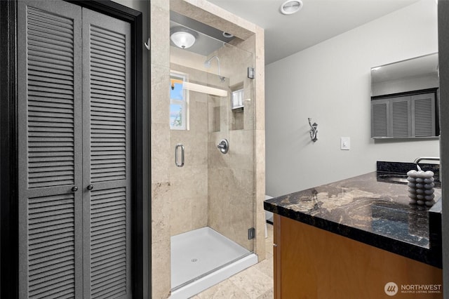 full bath with a shower stall, vanity, and a closet